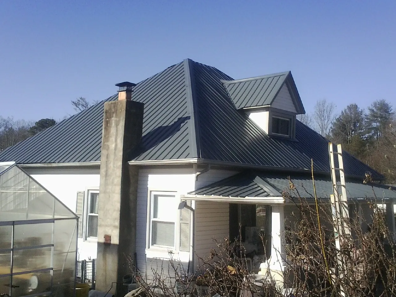 Dark blue standing seam metal roof on a white farmhouse with dormer — Slate & Tile Roof Repair by Roofing Brothers in Ainsworth