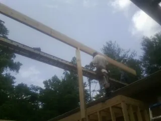 Carpenter setting a ridge beam over a new addition frame — Ice Dam Removal by Roofing Brothers in Ainsworth