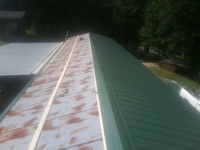 Old rusted panels beside newly installed green metal roofing — Wind Damage Roof Repair by Roofing Brothers in Ainsworth