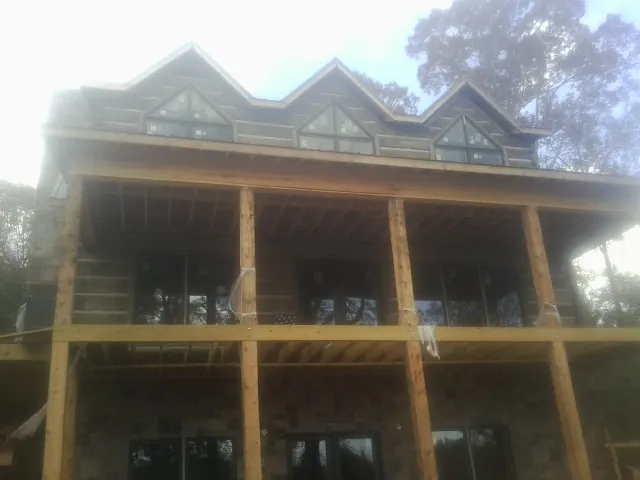Dormers and porch framing on a large log home under construction — Roof Coating work by our crew in Ainsworth